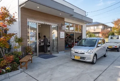 紅葉の販売店入口と銀色のコンパクトカー