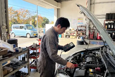 診断機でエンジン点検する整備士